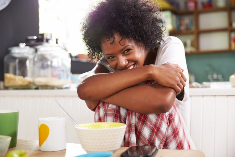 Portrait Of Young Woman Eating Breakfast In Kitchen
